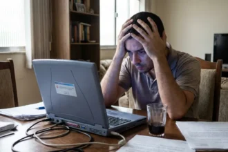 Um notebook aberto em uma mesa com um café, representando a busca por um notebook barato.